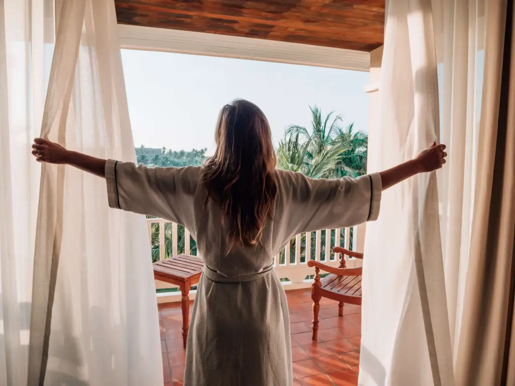 Nainen avaa verhot.